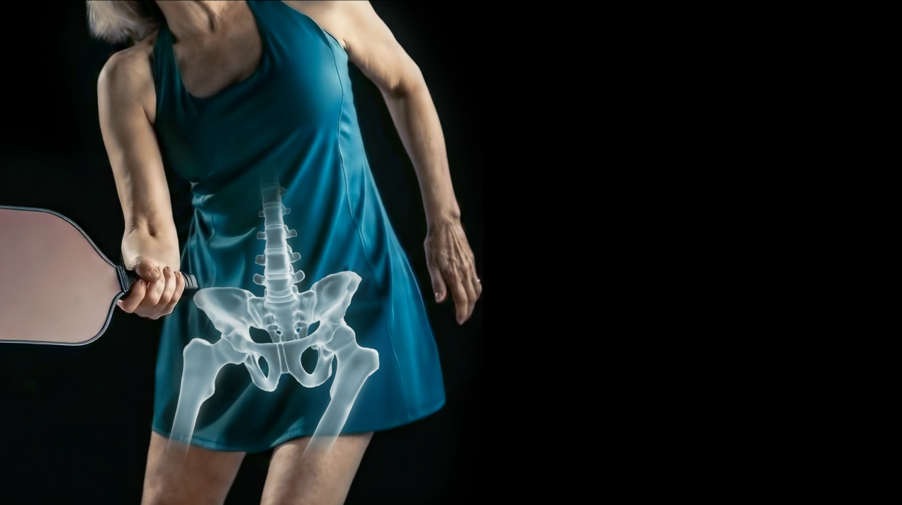 Torso of a female in a green dress holding a pickle ball racket