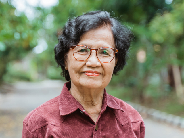 Middle-aged woman with red glasses and short dark hair and a red shirt